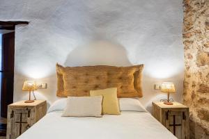 um quarto com uma cama branca e 2 candeeiros em Can Mateu em Santa Eulária des Riu