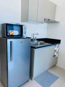 a kitchen with a microwave on top of a refrigerator at Makati Penthouse with Stunning City Skyline View in Manila