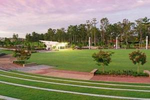 a large green field with a building in the background at The Arcadia - Entire Luxurious English Cottage With Huge Privacy Near CBD in Springfield Lakes