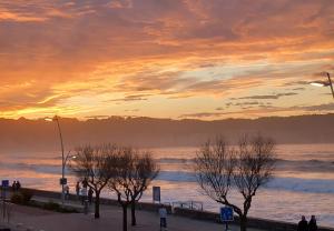 un tramonto sull'oceano con persone che camminano sulla spiaggia di Appartement bord de mer très lumineux 2/4 pers. - Vue inoubliable a Hendaye