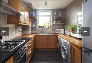 a kitchen with wooden cabinets and a stove top oven at Flat by Victoria park - with balcony in London