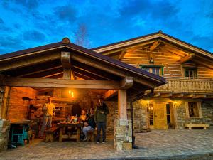 un gruppo di persone che si trovano fuori da una baita di tronchi di Chalet Laitner a Yasinia