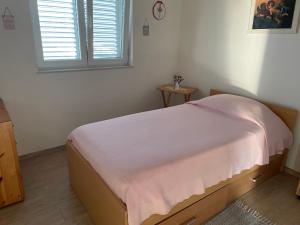 ein Schlafzimmer mit einem Bett mit einer rosa Decke darauf in der Unterkunft Island Escape in Mali Iž
