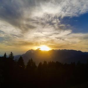 a sunset over a mountain range with the sun setting at Gruppenhaus Hirzhof in Auberg