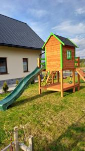 un parque infantil con tobogán y una casa en Apartament CEKO, en Ostrowsko