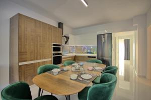 a dining room with a wooden table and green chairs at Casa Cafenio by PosarelliVillas in Nípos