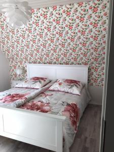 een slaapkamer met een wit bed en bloemenbehang bij Ferienwohnung mit Seeblick - a84916 in Jemgum