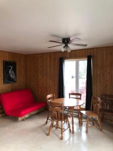 a living room with a table and a red couch at Chalets les chanterelles de Forillon in L’Anse-au-Griffon