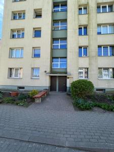 a building with a bench in front of it at LUNA Apartamentai in Akmenė