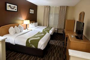 a hotel room with two beds and a flat screen tv at Quality Suites Near West Acres in Fargo