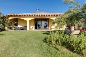 una pequeña casa amarilla con un gran patio en Vivi Natura, en Marrùbiu