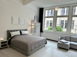 a bedroom with a bed and a chair and windows at MEOS 2 -Zentrum-Hofblick-Gym-Netflix in Leipzig