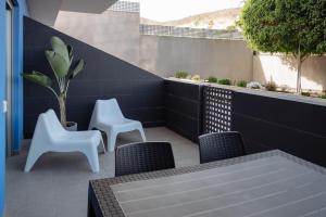 a patio with two white chairs and a table at Cornisa Apartments in Patalavaca