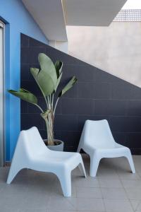 two white chairs and a plant in a room at Cornisa Apartments in Patalavaca