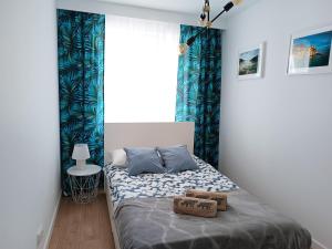 um pequeno quarto com uma cama com cortinas azuis em Apartament nr15 z parkingiem podziemnym em Toruń