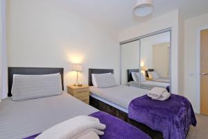 a bedroom with two beds and a mirror at Caledonia Newhills Apartment in Aberdeen