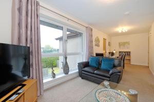 uma sala de estar com um sofá e uma grande janela em Caledonia Newhills Apartment em Aberdeen