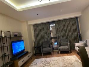 uma sala de estar com televisão e duas cadeiras em Low Price Luxury Apartment Perfect for An Amazing stay In Istanbul em Istambul