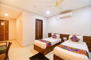 a hotel room with two beds and a tv at FabHotel Royal Crystal in Bhubaneshwar