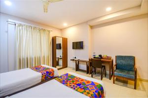 a hotel room with a bed and a desk and a chair at FabHotel Royal Crystal in Bhubaneshwar