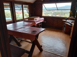 uma cozinha com uma mesa de madeira num quarto com janelas em Casa Rariana em Călimăneşti