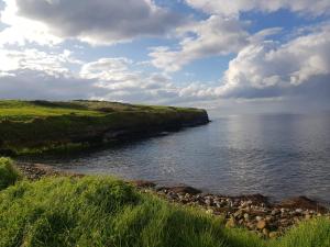 a large body of water with a grassy hill next to the ocean at Coastal Cottage in Dromore West