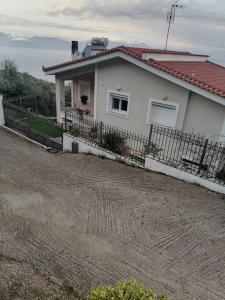 a white house with a fence in front of it at White Hill Platanos in Akrata