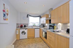 uma cozinha com armários de madeira e uma máquina de lavar e secar roupa em Caledonia Newhills Apartment em Aberdeen