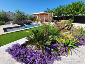 een tuin met paarse bloemen en een zwembad bij Villa Tropez Chambres d'hôtes in Le Luc