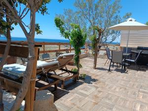 a patio with a table and chairs and an umbrella at Vila Apostolis in Agios Pavlos
