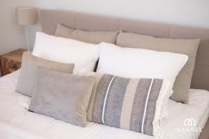 a pile of pillows on top of a bed at Apartament Sea View - Pinea Apartments Pobierowo in Pobierowo