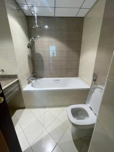 a bathroom with a tub and a toilet and a sink at Lovely 2 BHK just 2 min from the beach in Ajman 