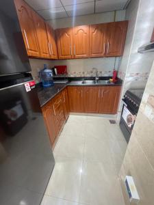 a small kitchen with wooden cabinets and a sink at Lovely 2 BHK just 2 min from the beach in Ajman 