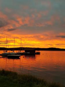 un grupo de barcos sentados en el agua al atardecer en Luksusowy apartament Charzykowy en Charzykowy