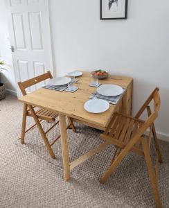 a wooden table with two chairs and plates on it at Studio Apartment North Cardiff in Cardiff