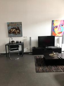 a living room with a flat screen tv and a table at À proximité de Strasbourg in Kilstett