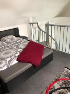 a bedroom with a bed with a red blanket on it at À proximité de Strasbourg in Kilstett