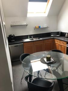 a kitchen with a glass table and black chairs at À proximité de Strasbourg in Kilstett +3 photos