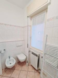 La salle de bains blanche est pourvue de toilettes et d'un lavabo. dans l'établissement Appartamento San Giorgio, à Lovere