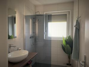 a bathroom with a sink and a shower with a window at Haus im Seegebiet von Villach in Villach