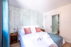 um quarto com uma cama branca e almofadas cor-de-rosa em Acogedor apartamento en Puerto de la Cruz em Puerto de la Cruz