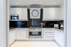een witte keuken met witte kasten en een oven bij Little Venice House in Londen