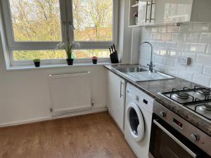 a kitchen with a sink and a washing machine at Morden 2 bedroom Apartment tower bridge in London