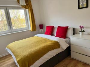 a bedroom with a bed with red pillows and a window at Morden 2 bedroom Apartment tower bridge in London