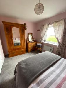 a bedroom with a bed and a dresser and a window at Moonstone in Beadnell
