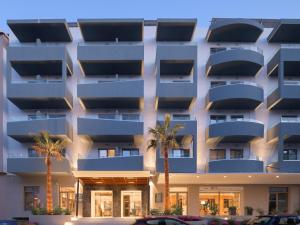 an apartment building with palm trees in front of it at Bio Suites Hotel in Rethymno