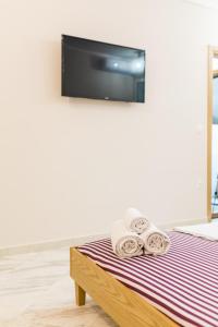 una camera con un letto con asciugamani e una TV a parete di Xsoma Flats Morfeas a Salonicco