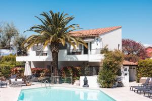 a palm tree in front of a building with a swimming pool at Hôtel La Villa Cap d’Antibes in Juan-les-Pins