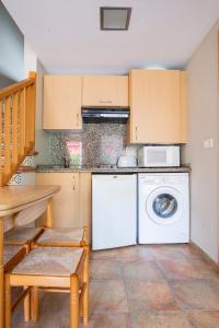 une cuisine avec un lave-linge blanc et une table dans l'établissement Apartamentos Aldea del Puente, à Cangas de Onís