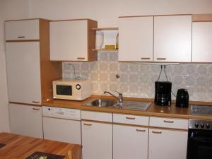 Apartment Seeblick Wetter في ويتير: مطبخ بدولاب بيضاء ومغسلة وميكروويف